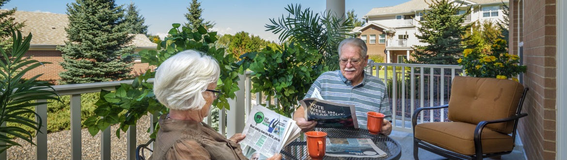 older couple reading newspaper on patio