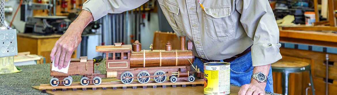 Man polishing wooden train